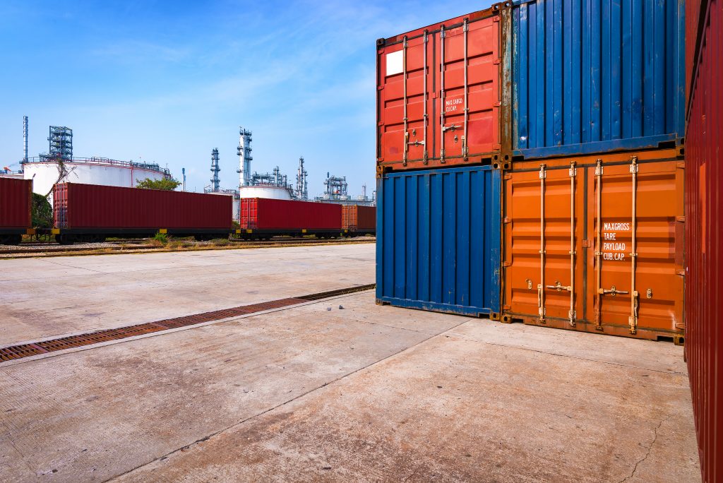 Shipping and Industry scene with Container, Freight Train and oil refinery plant in background.